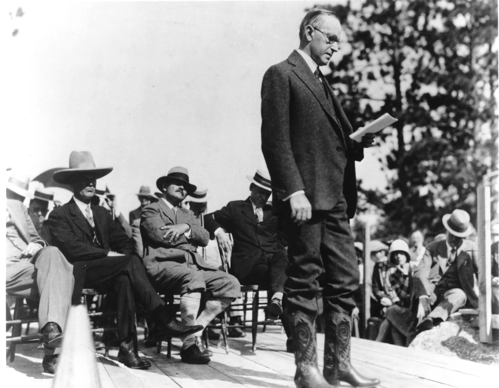President Coolidge dedicates the site that will be the Mount Rushmore Memorial, August 10, 1927. Flamboyant sculptor, Gutzon Borglum is seated cross-legged directly behind the standing President. 